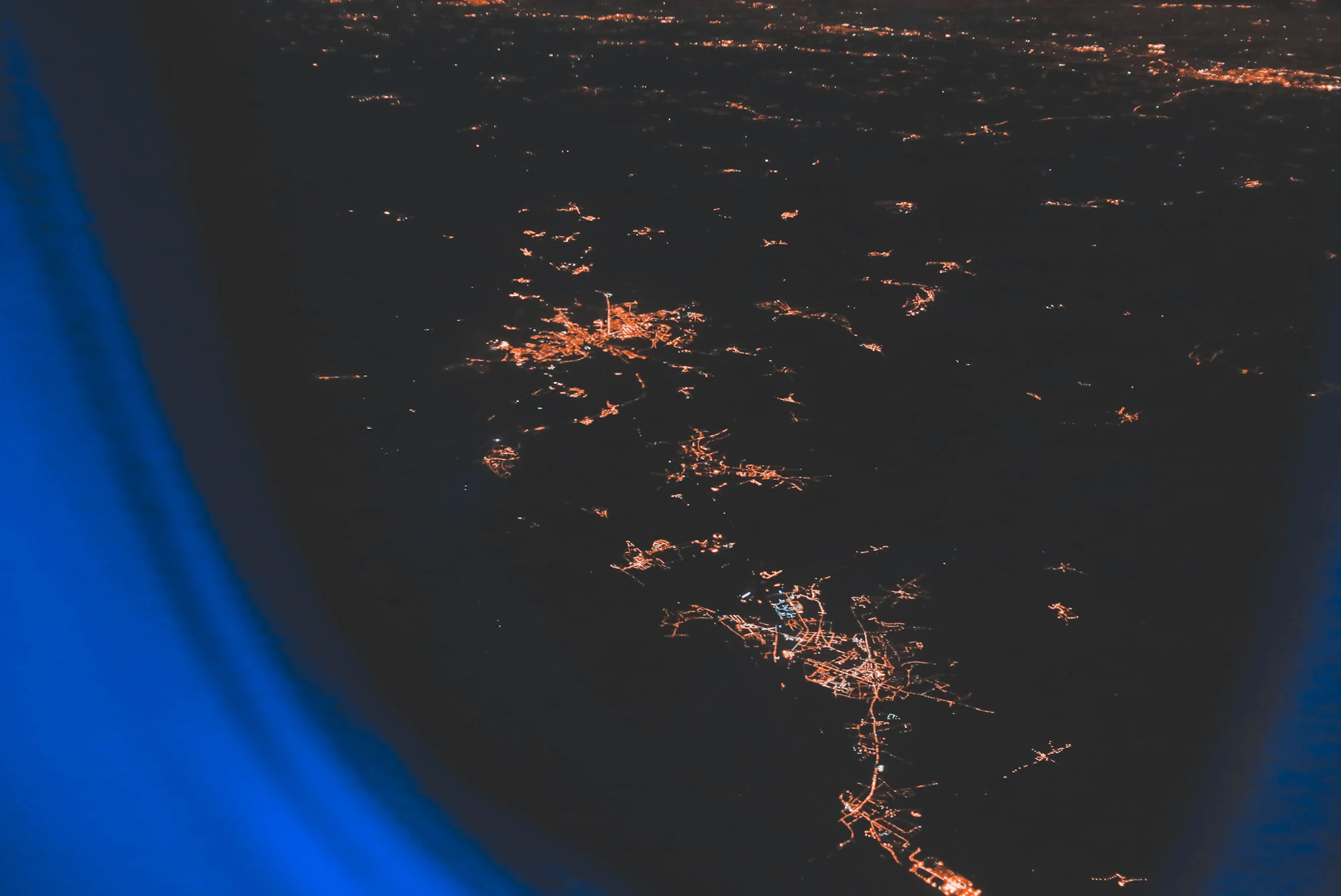 Cidade vista de cima, à noite, pela janela do avião