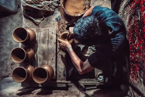 An artisan shaping clay on a potter’s wheel, surrounded by tools and splashes of colorful glaze.