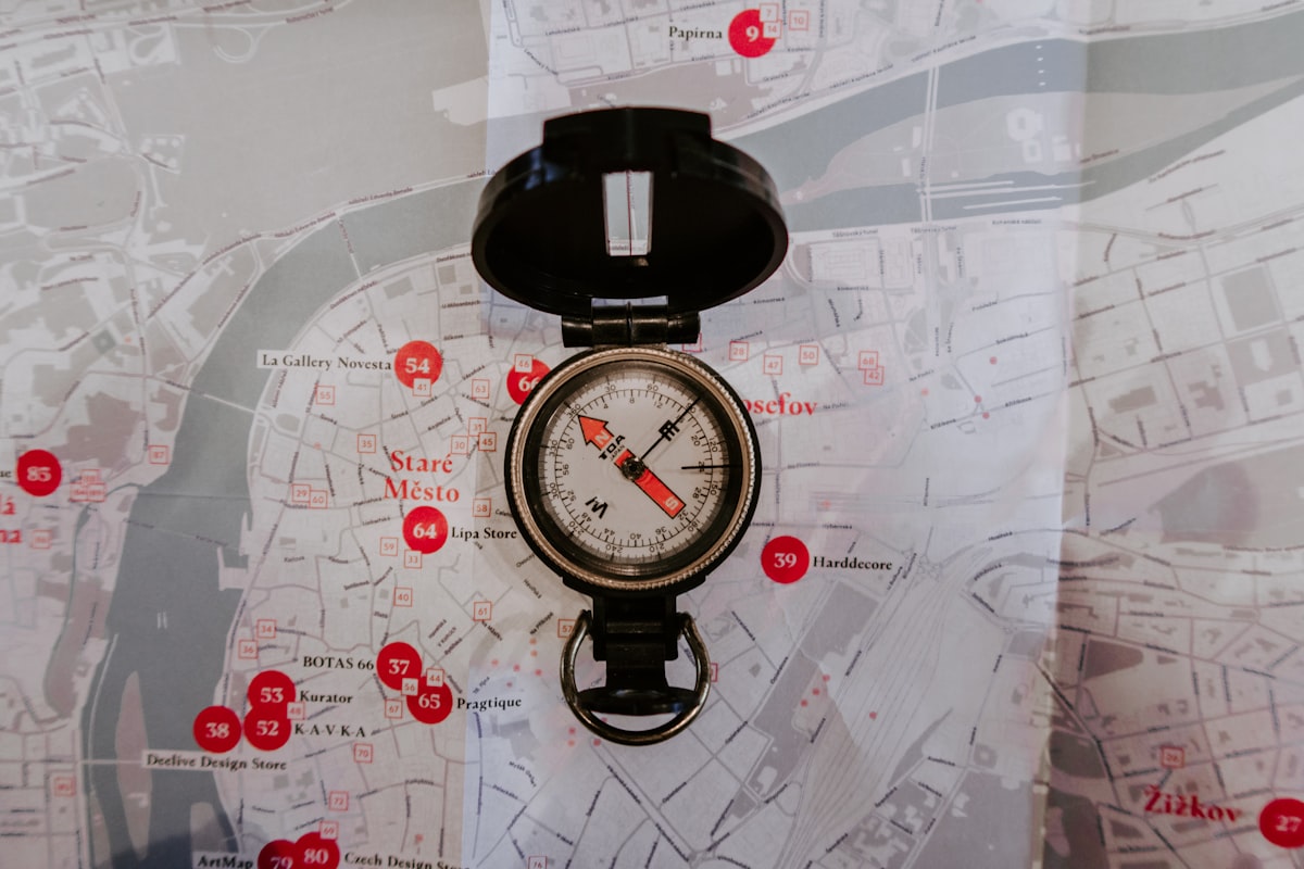 A metal compass resting on a printed map, representing the work of orienting yourself in a new market before entering it