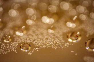 Close-up of golden skin oil droplets glistening on a smooth glass surface with soft natural light
