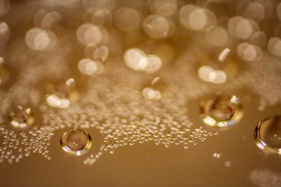 Close-up of golden skin oil droplets glistening on a smooth glass surface with soft natural light