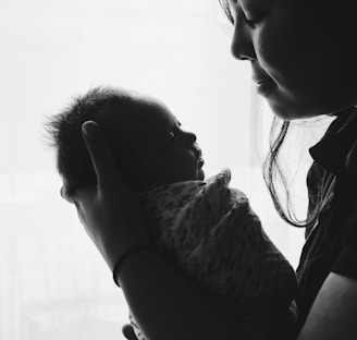grayscale photography of woman carrying a baby