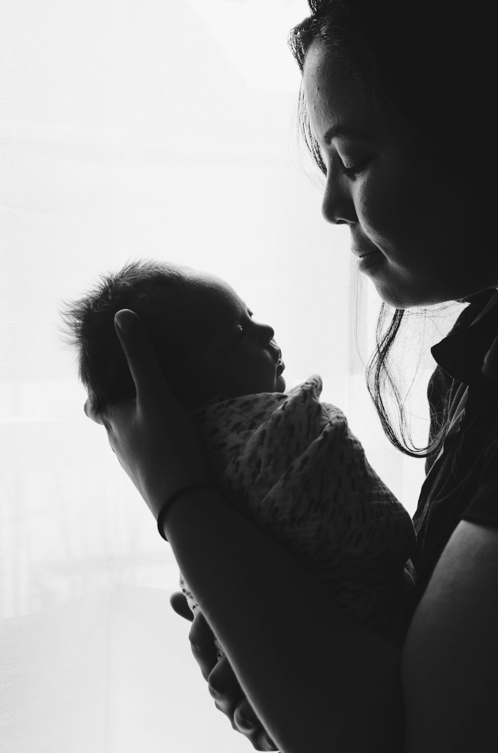 grayscale photography of woman carrying a baby