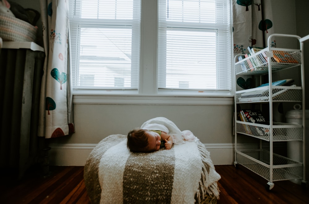 baby sleeping on gray and white bed