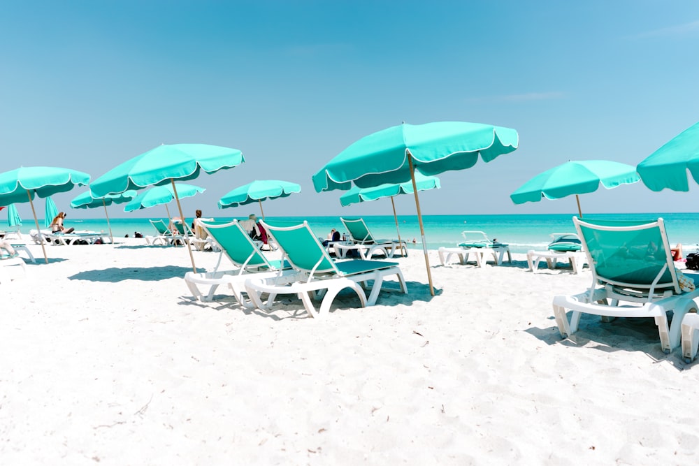 낮에는 해변의 흰색과 녹색 안락 의자와 캐노피 우산