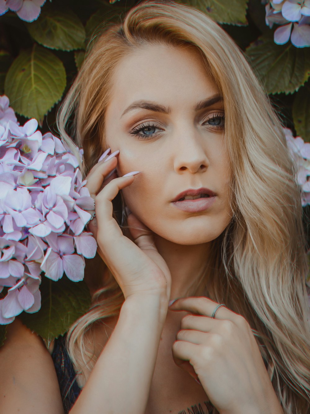 woman standing beside purple-petaled flowers