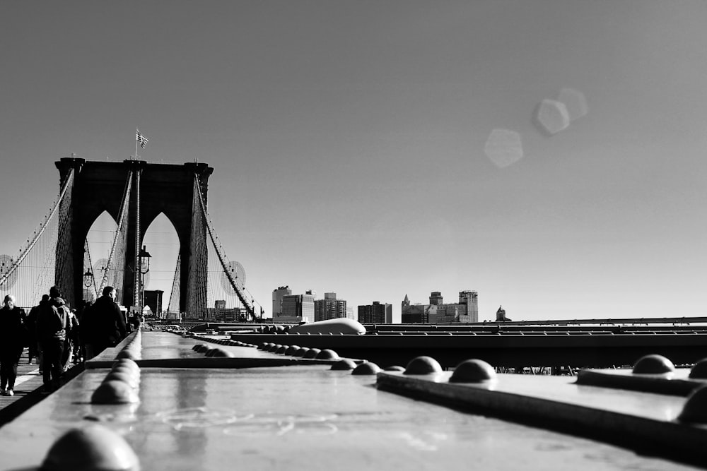 grayscale photography of people walking on Brooklyn Bridge