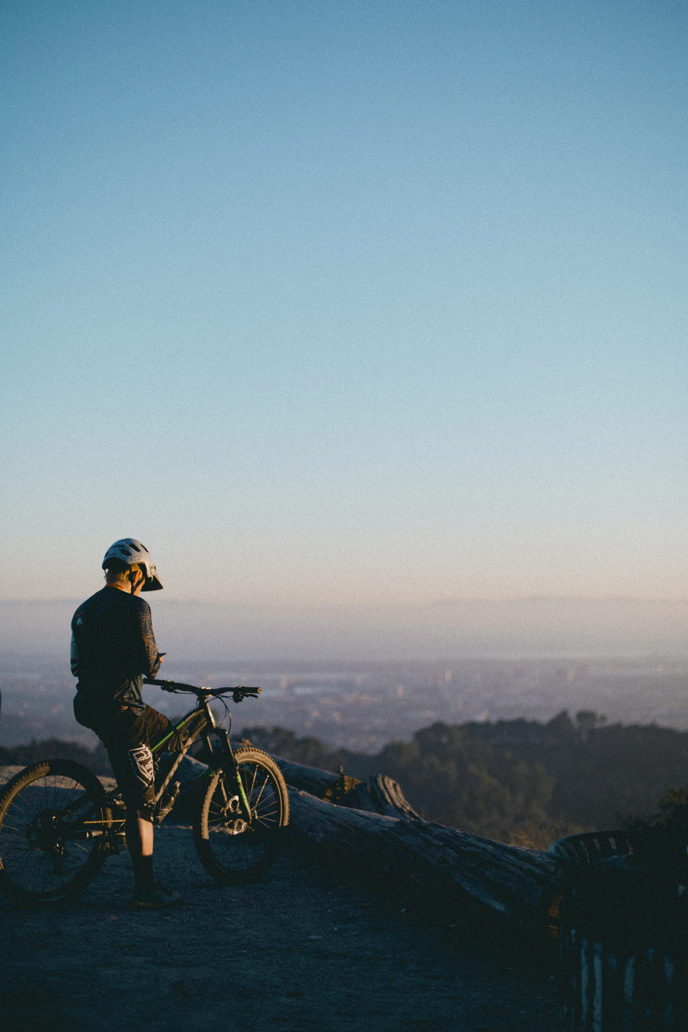 A rider in a helmet looking out over a hazy valley at dusk