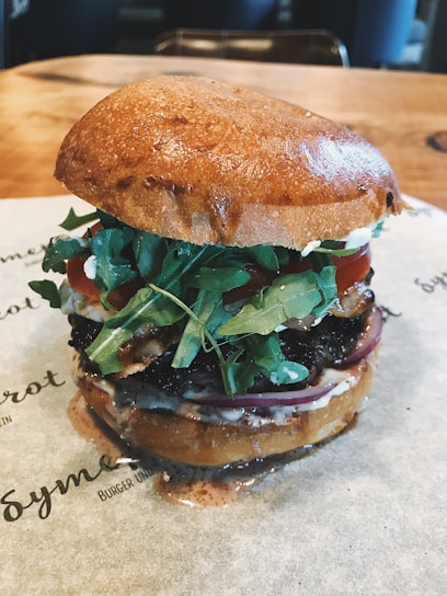 Close-up of a gourmet burger with fresh toppings on a wooden table.