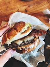 Close-up of a juicy gourmet burger with fresh toppings on a rustic wooden table.
