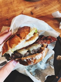 Close-up of a juicy gourmet burger with fresh toppings on a rustic wooden table.