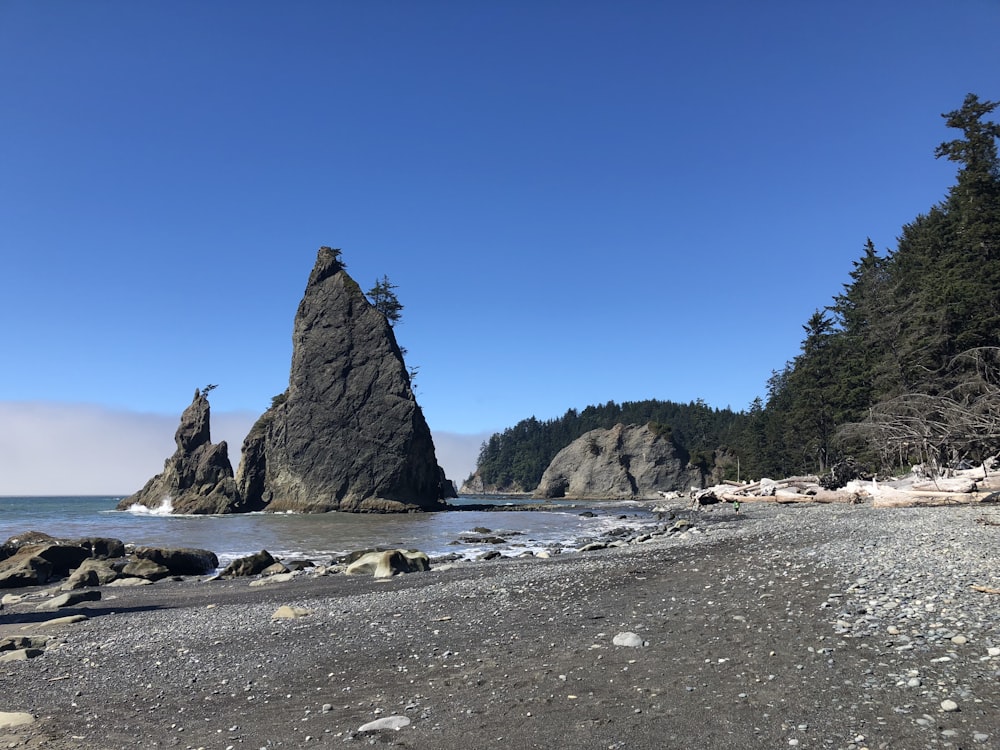 gray concrete boulder surrounded by body of water