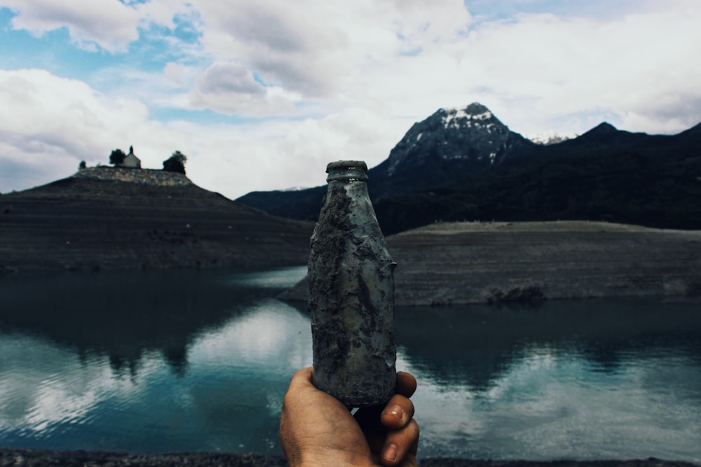 person holding clear glass bottle