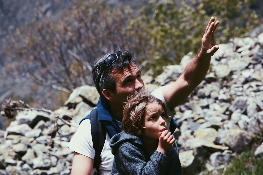 boy standing in front of man near rocky terrain during daytime