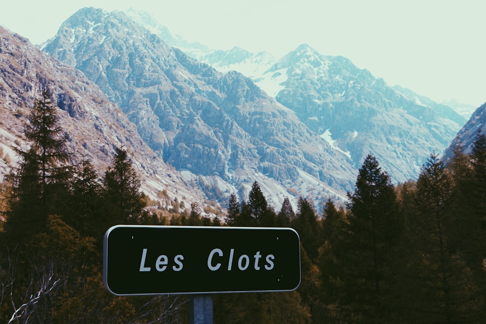 Les Clots signage with trees and mountain in background at daytime