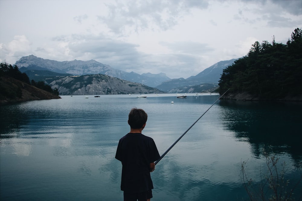 boy fishing on calm water at daytime
