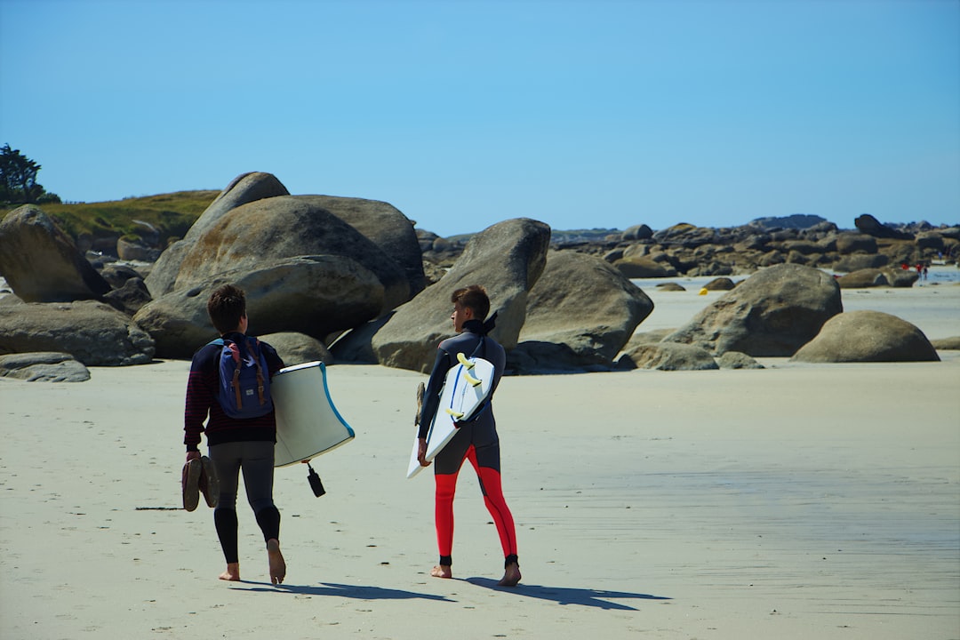 two person with surfboards walking on seashore