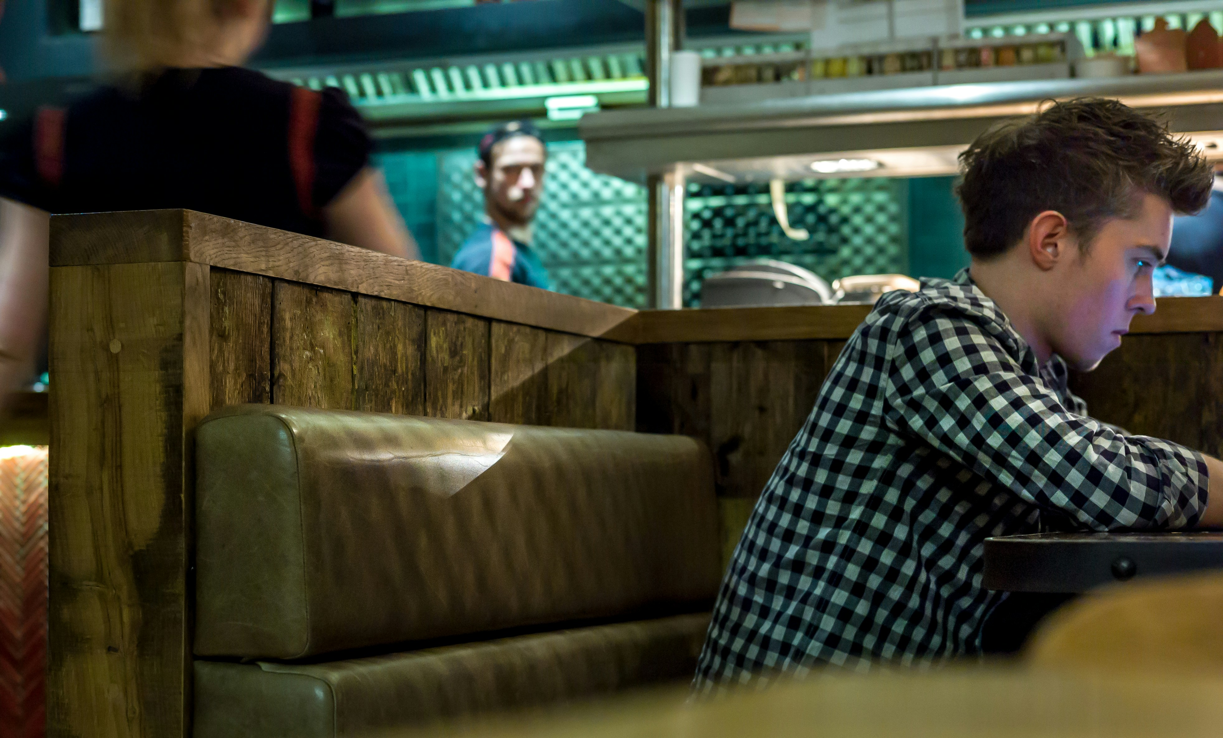 man in black, white, and gray flannel shirt sitting in front of table