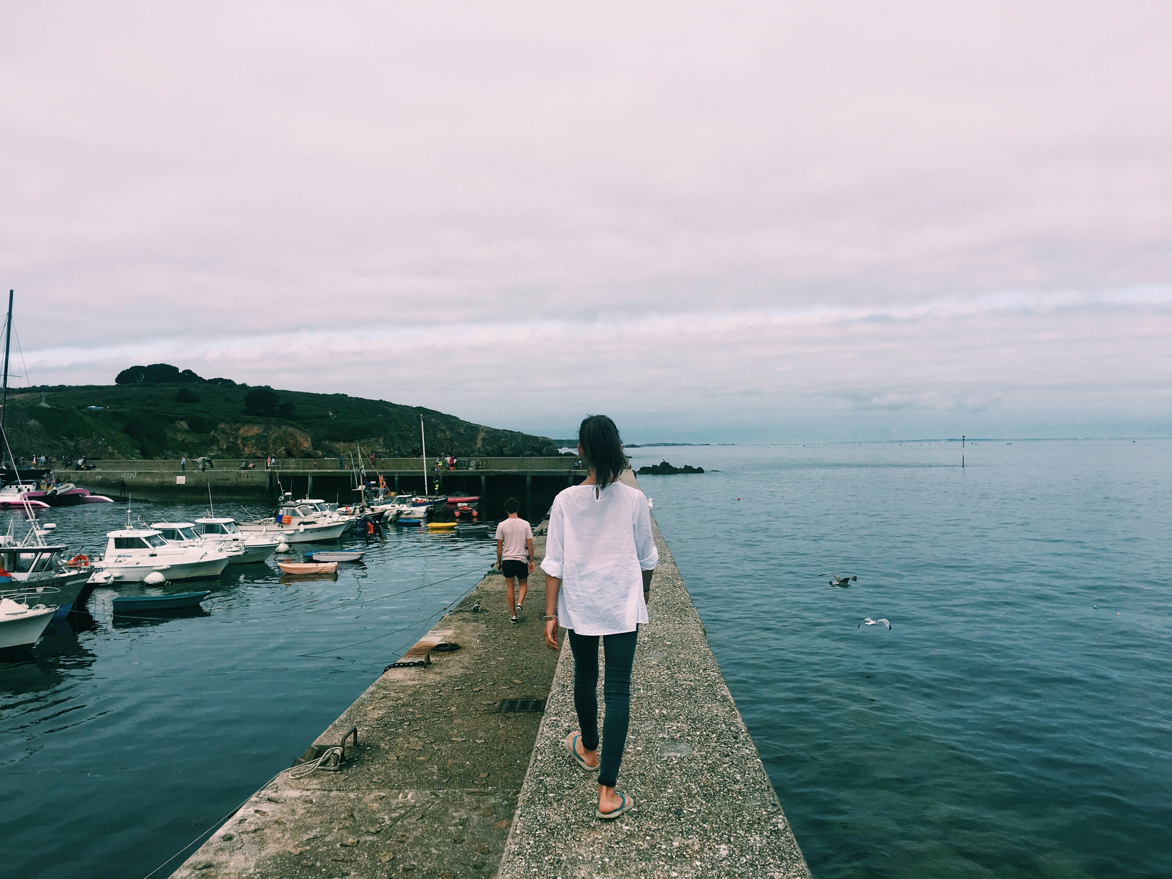 femme marchant sur le quai avec des bateaux sur le côté