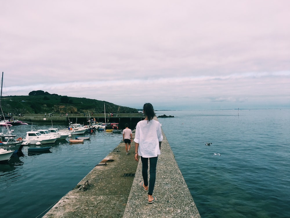 woman walking on dock with boats on the side