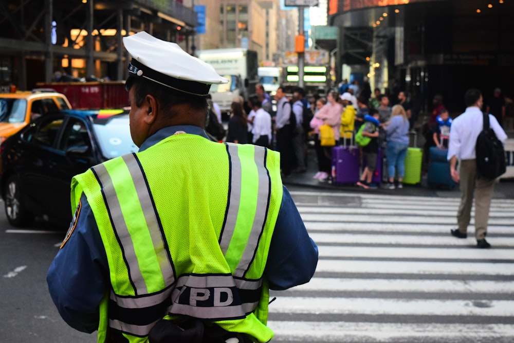 man wearing auxiliary vest standing near pedestrian lane