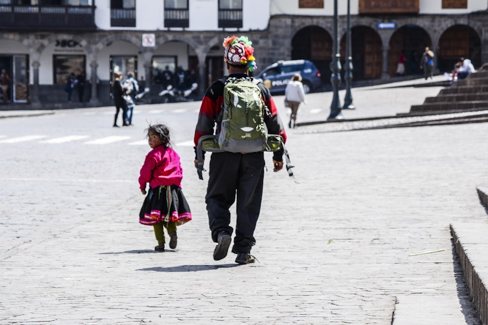 man and girl walking on road near building