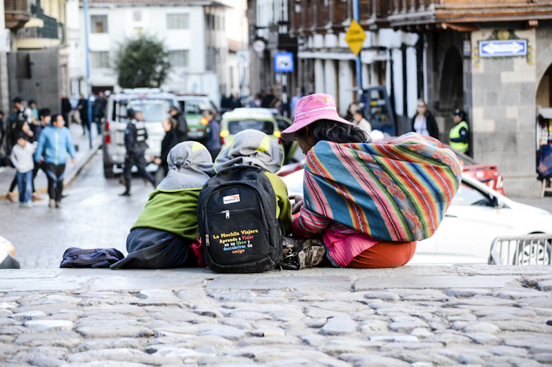 Children with backpacks sitting on a Cusco street in the afternoon