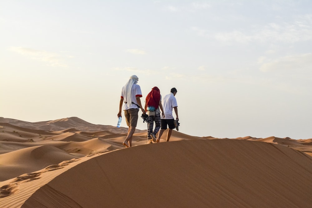 three men walking on desert during daytime