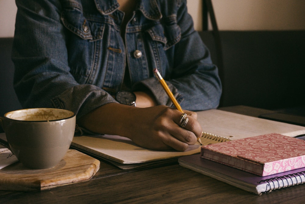 woman writing on paper inside well-lit room