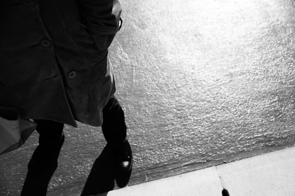 a black and white photo of a person walking down a sidewalk