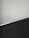 A simple interior corner with a white wall and a dark floor separated by a thin metallic strip. The wall has light scratches visible upon close inspection.