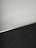 A simple interior corner with a white wall and a dark floor separated by a thin metallic strip. The wall has light scratches visible upon close inspection.
