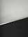 A simple interior corner with a white wall and a dark floor separated by a thin metallic strip. The wall has light scratches visible upon close inspection.