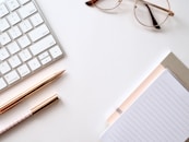 pen near black lined paper and eyeglasses