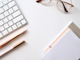 pen near black lined paper and eyeglasses