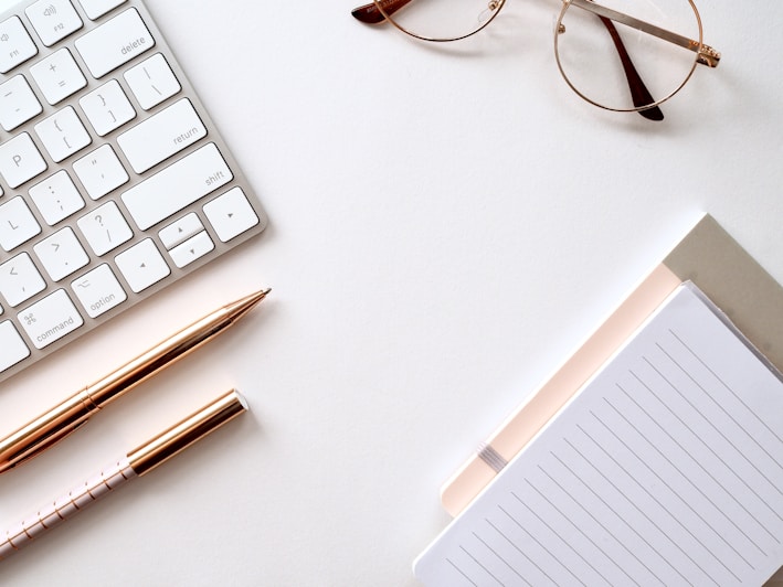 A neatly arranged desk featuring elegant notebooks and pens from Naweis LLC.