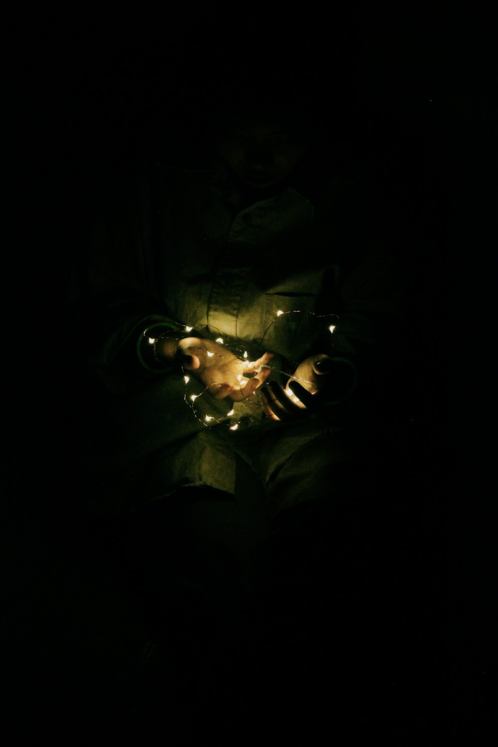 woman holding string light in dimmed room