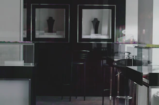 A dark, cinematic exhibition space with elegant lighting and minimalist displays.