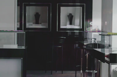 A dark, cinematic exhibition space with elegant lighting and minimalist displays.