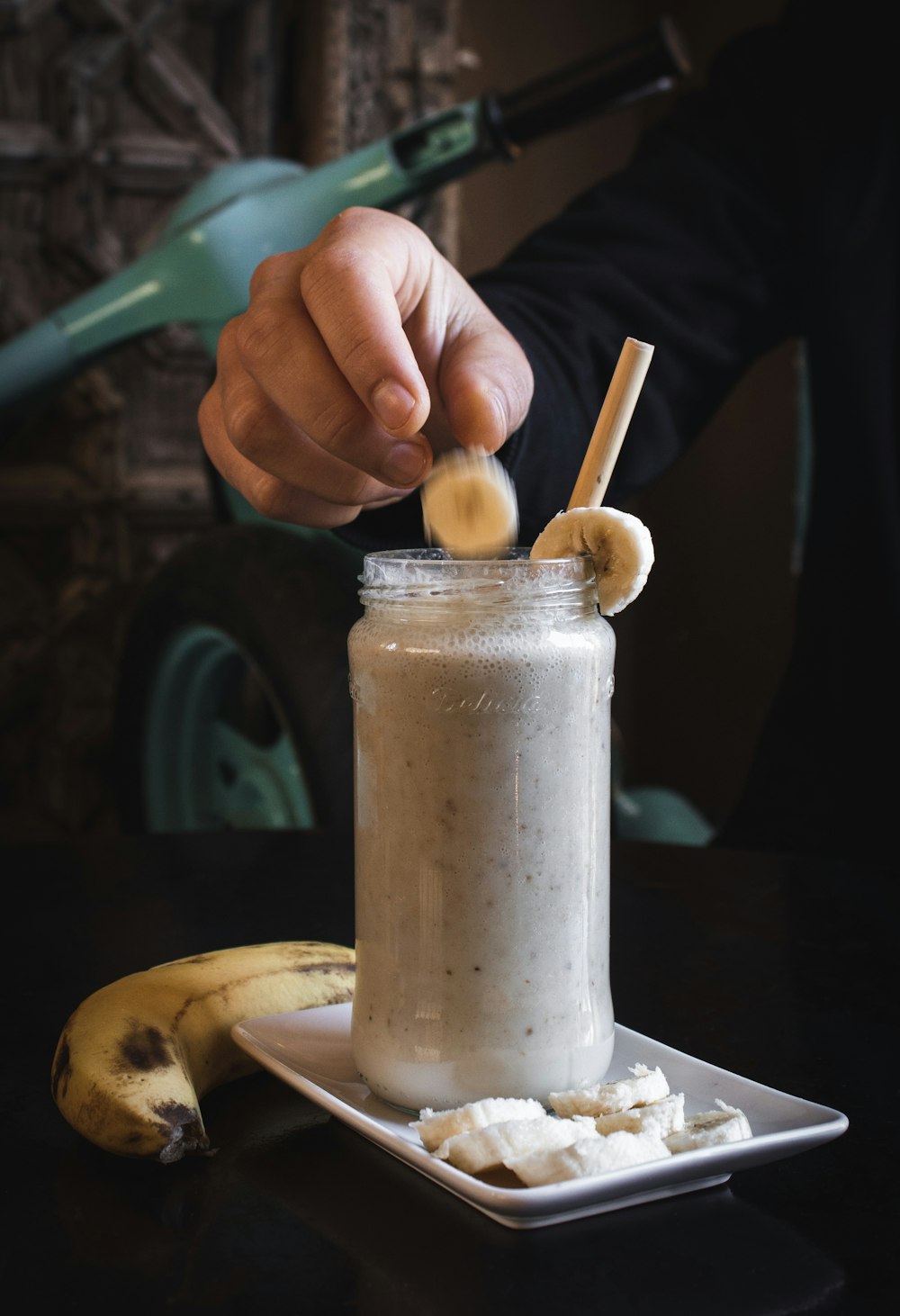 person putting sliced banana fruit on top of jar