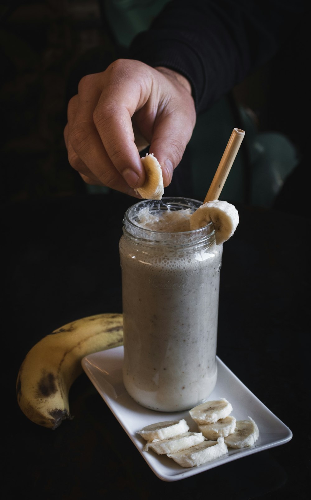 person holding slice of banana on fruit shake har