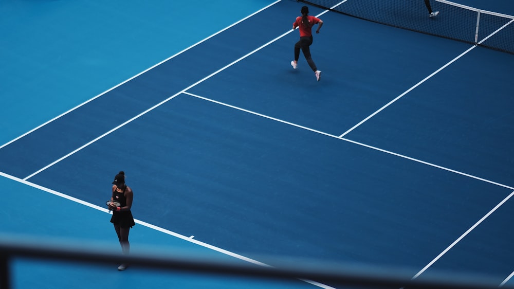 two person playing tennis during daytime