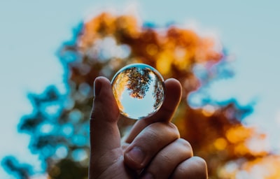 selective focus photography of person holding clear ball planet teams background