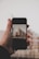 A close-up of a hand holding a smartphone displaying real estate listings.