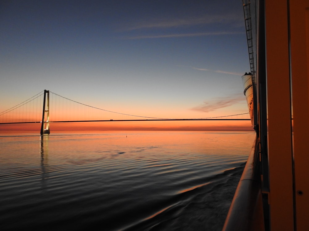 boat on body of water near bridge during golden hour