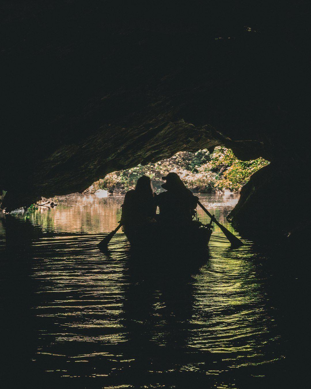 two person boating under cave during daytime