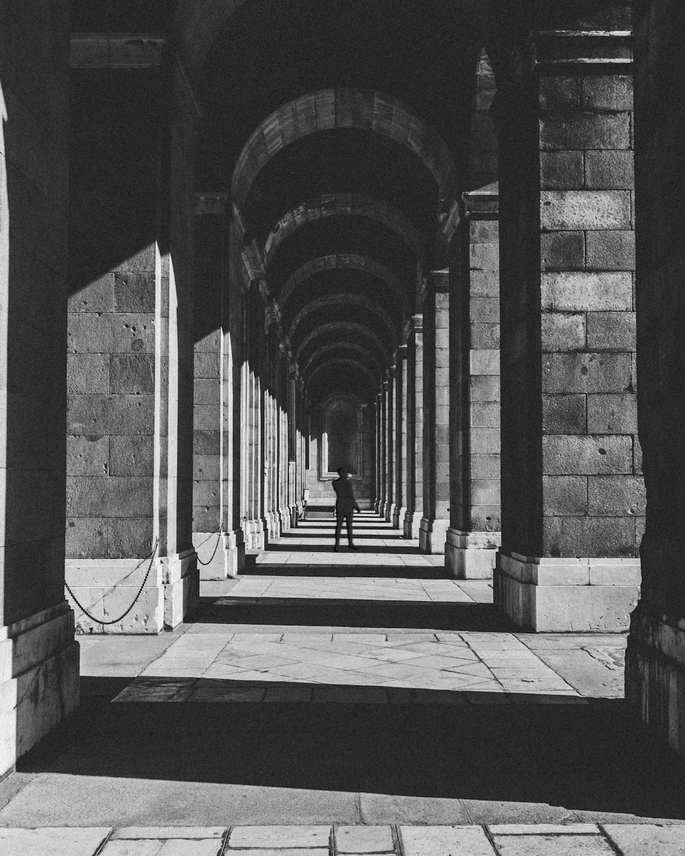 silhouette of person beside brick walls in grayscale photography