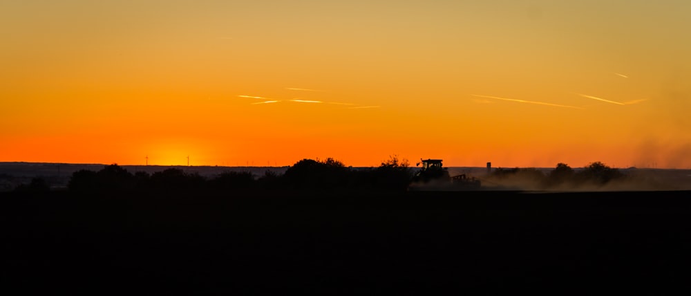 the sun is setting over a field with smoke coming out of it