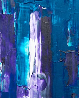 Abstract painting with bold, vertical brushstrokes in shades of blue, teal, purple, and white. The textured surface creates a sense of depth and movement.