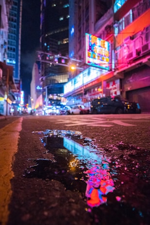 A vibrant glow sign illuminating a busy street corner at night with vivid colors.